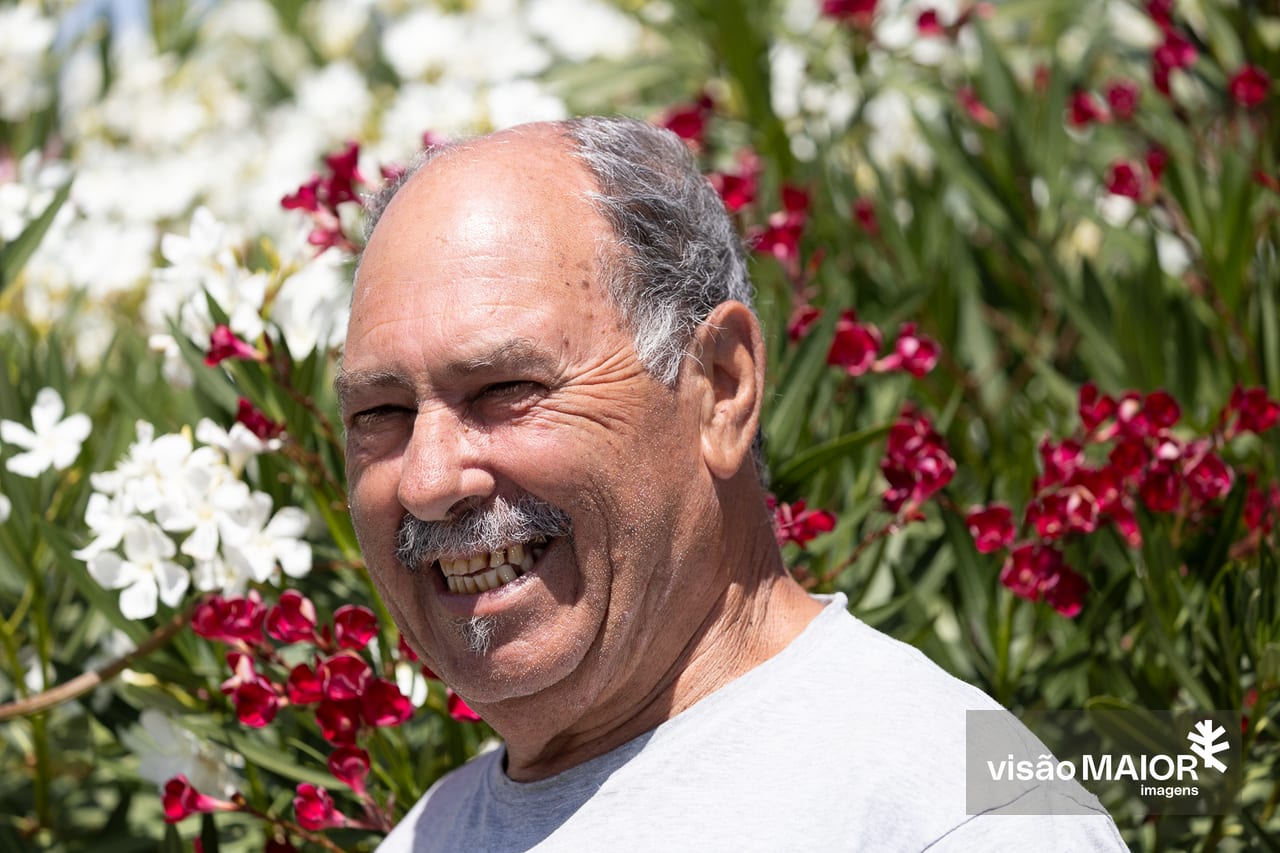 Homem careca, com bigode e pouco cabelo grisalho a sorrir